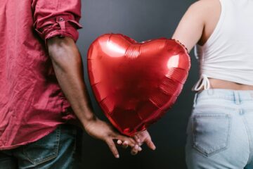 couple holding a red heart shaped balloon