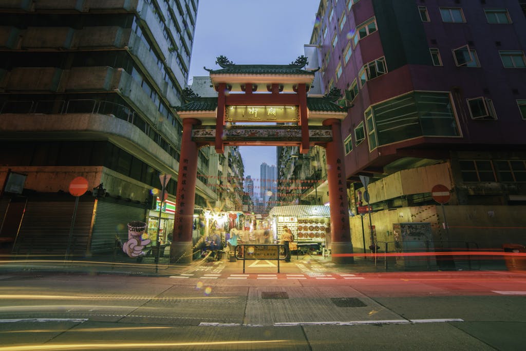 Colorful street view of Mong Kok with vibrant nightlife and traditional Chinese gate in Kowloon, Hong Kong.