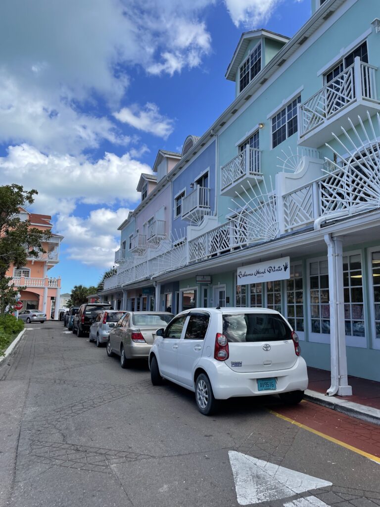 A residential street in Nassau with cars parked on the side of the road next to the house building.