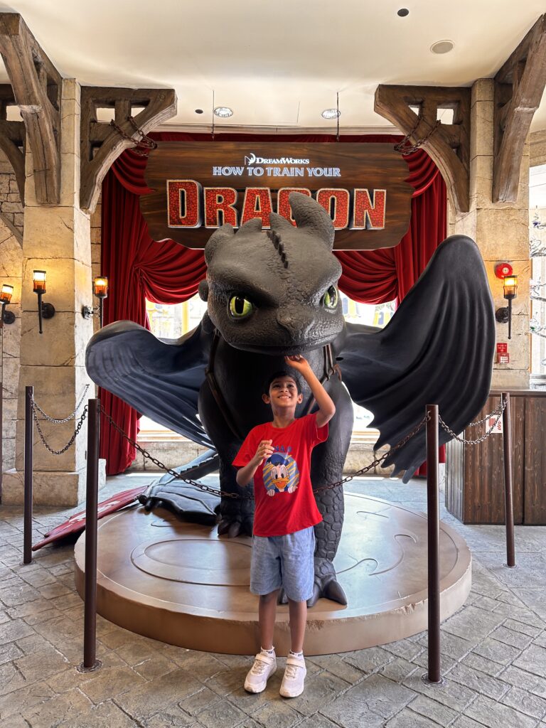 A boy standing below Night Fury at Universal Studios Singapore